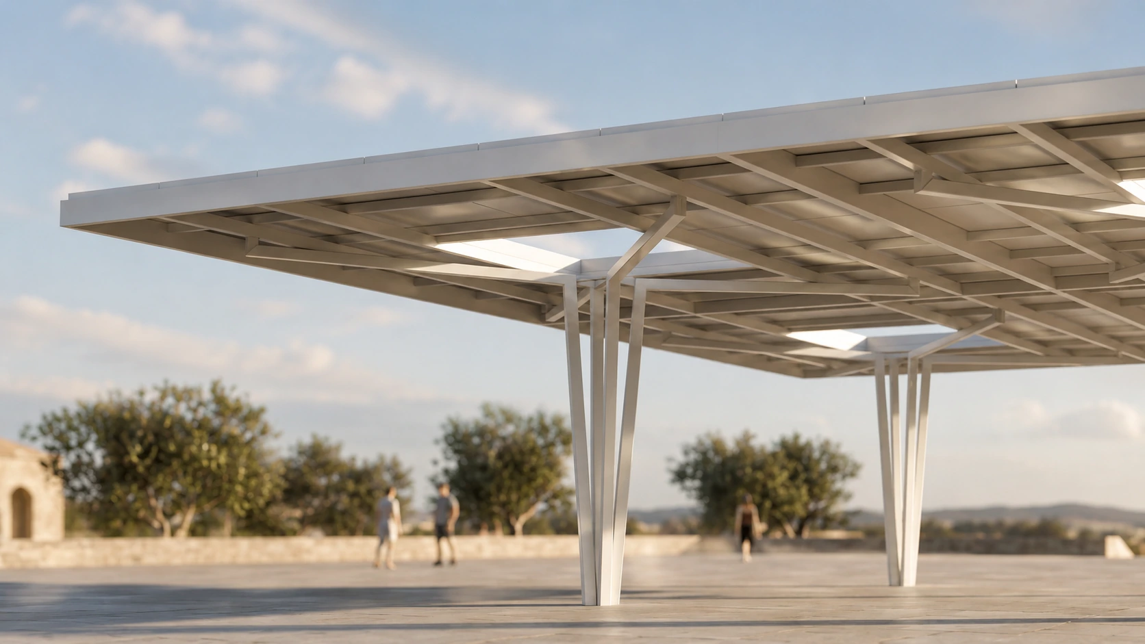 Low-angle view of a large white steel canopy with angular supporting legs over a paved plaza, with people blurred in the background.